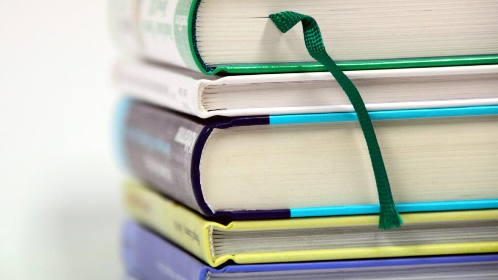 Stack of hardcover books with a green ribbon bookmark