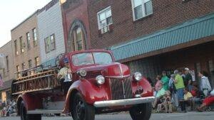 Vintage red fire truck rolling down a small town parade route