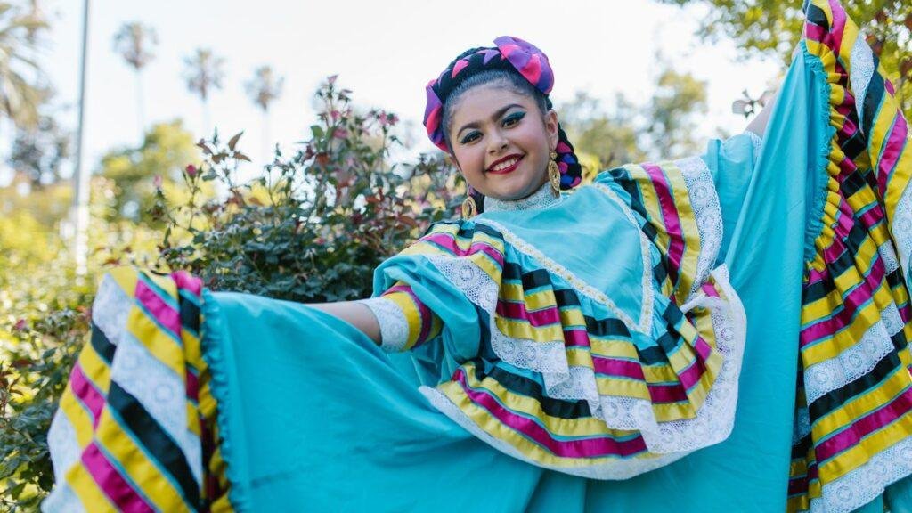 Ballet folklorico dancer holding out the wide turquoise skirt of her dress