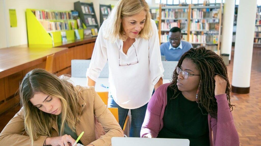 A librarian helping two students working at a laptop
