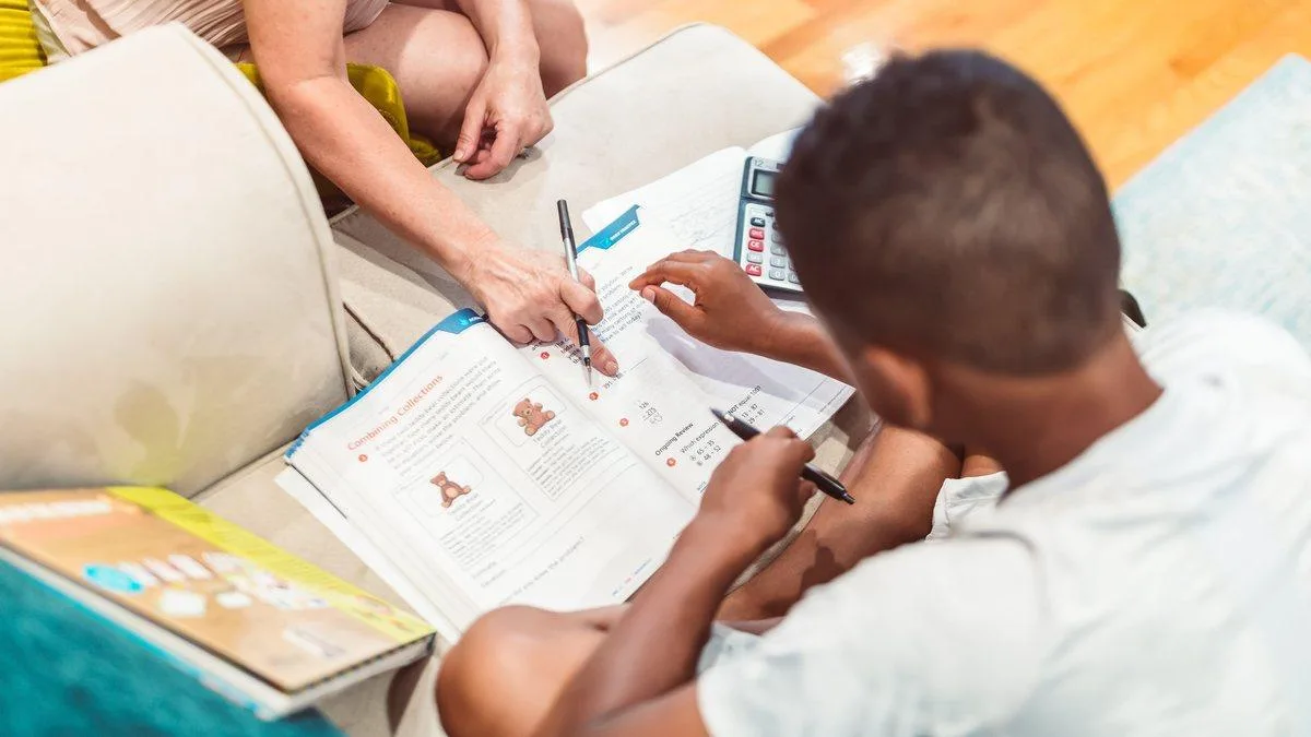 An adult helping a student work through a lesson at a table