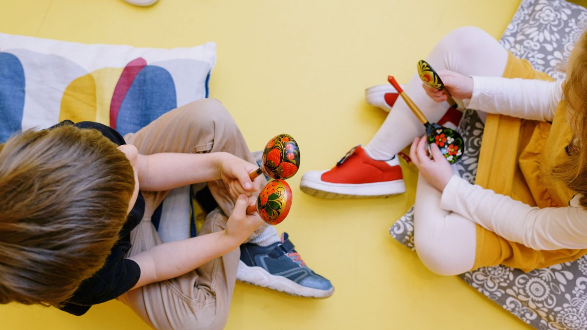 Young children sitting on the floor playing with maracas