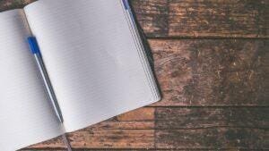 Open notebook and pen on a wooden desk