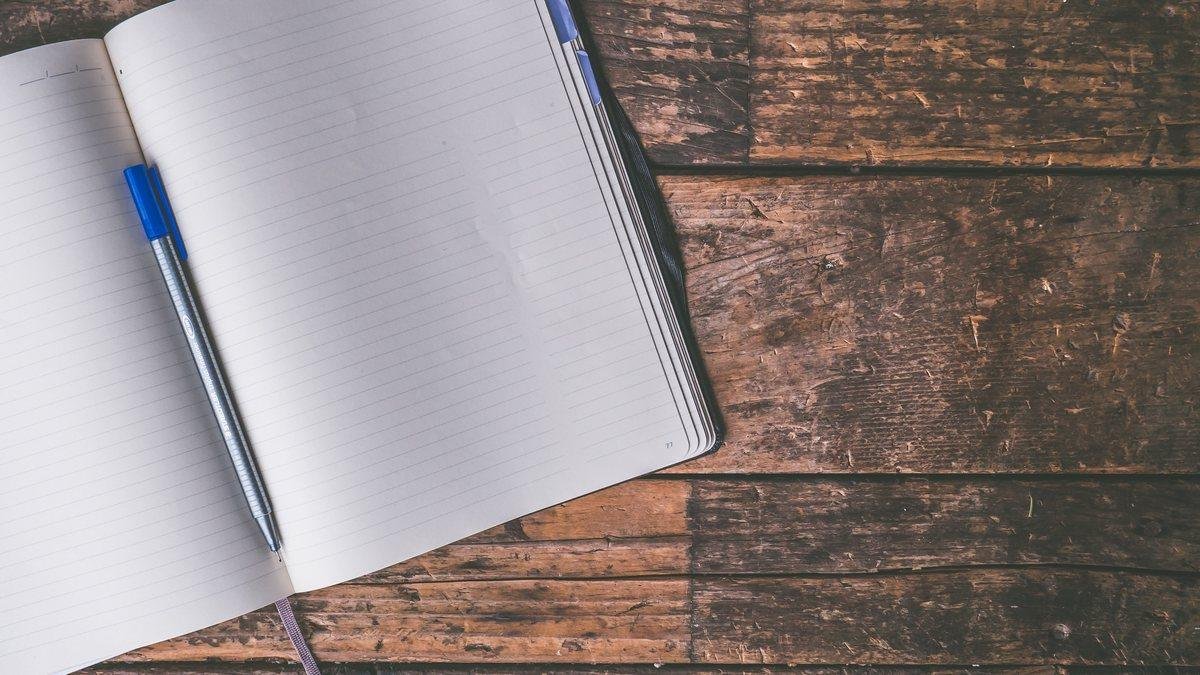 Open notebook and pen on a wooden desk