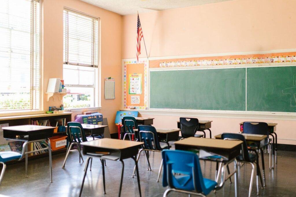 Empty classroom with rows of desks lit by sunlight from the windows