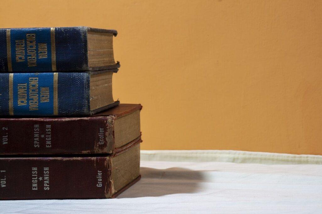Stack of old English-Spanish dictionaries on a table against a warm wall