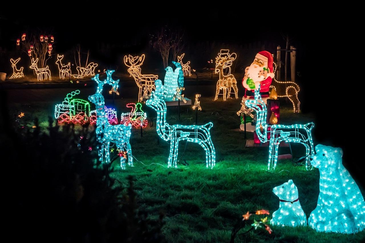Light-up reindeer and Santa figures glowing on a lawn at night