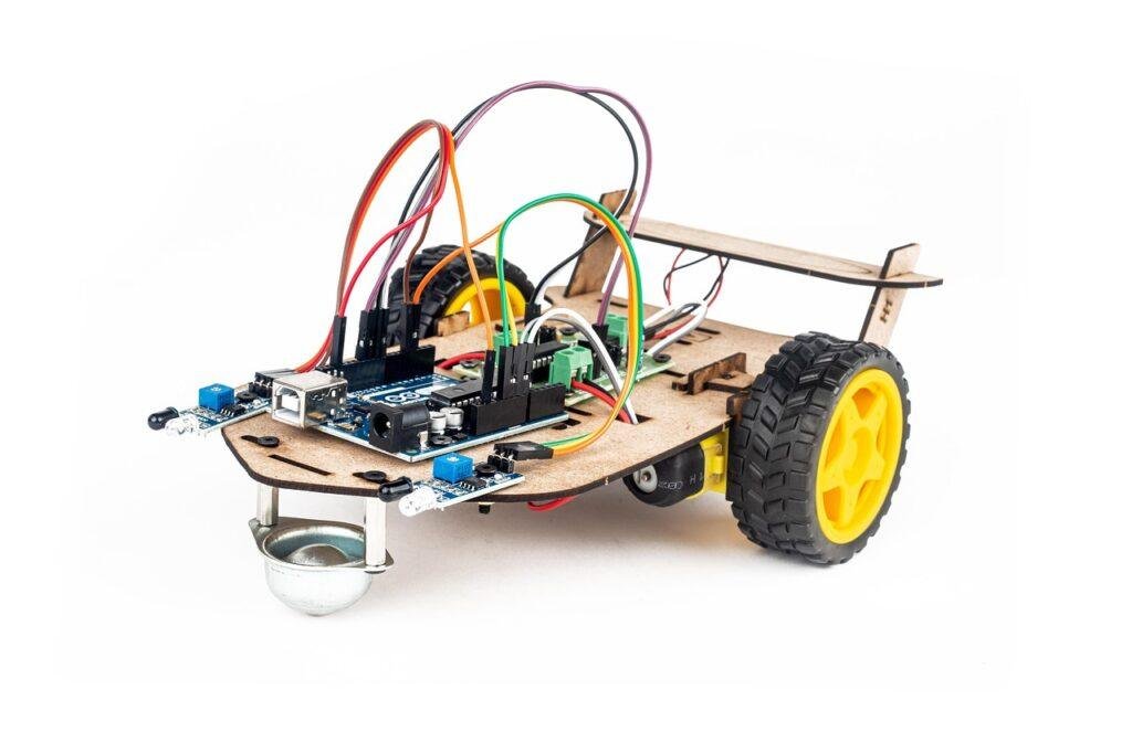 Small wheeled robot car kit with colorful wires and a circuit board