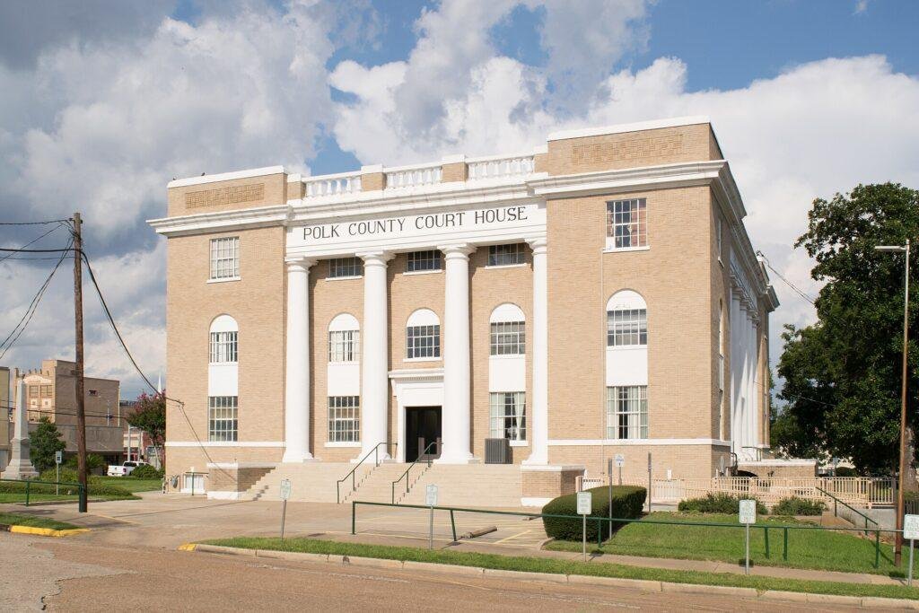 Front of the tan brick Polk County Courthouse in Livingston, Texas, with white columns and front steps
