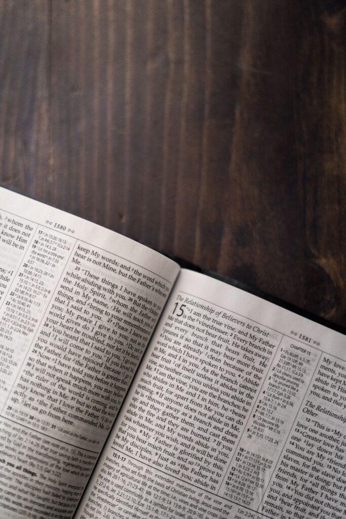 An open Bible resting on a dark wooden table in soft light