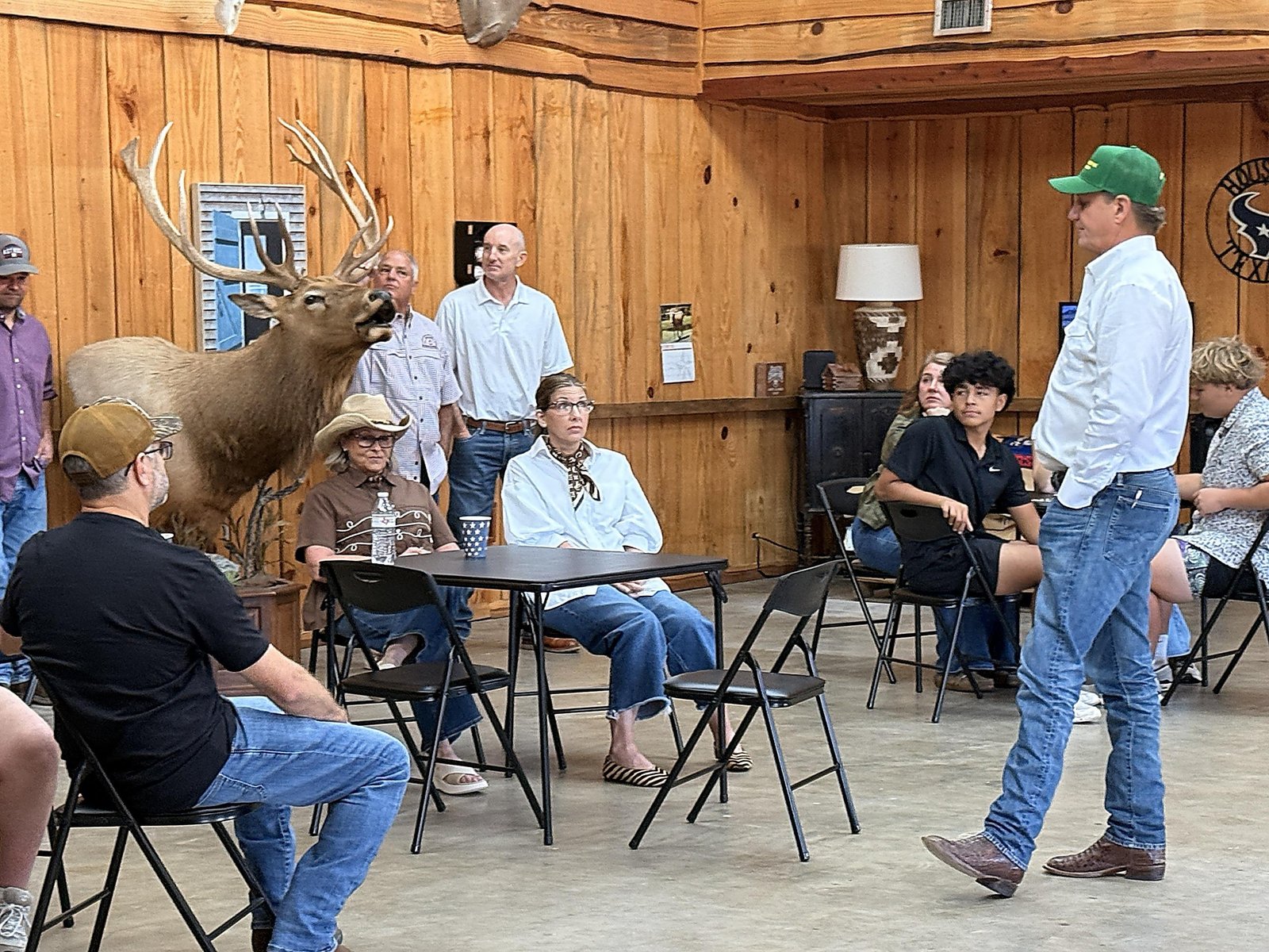 Nate Sheets, in a green cap, talks with guests beside a mounted bull elk. Seated at the table are host Lisa Sailer, left, and Allison Evans. Host Kevin Sailer and Livingston Mayor-elect Andy Evans stand behind them.