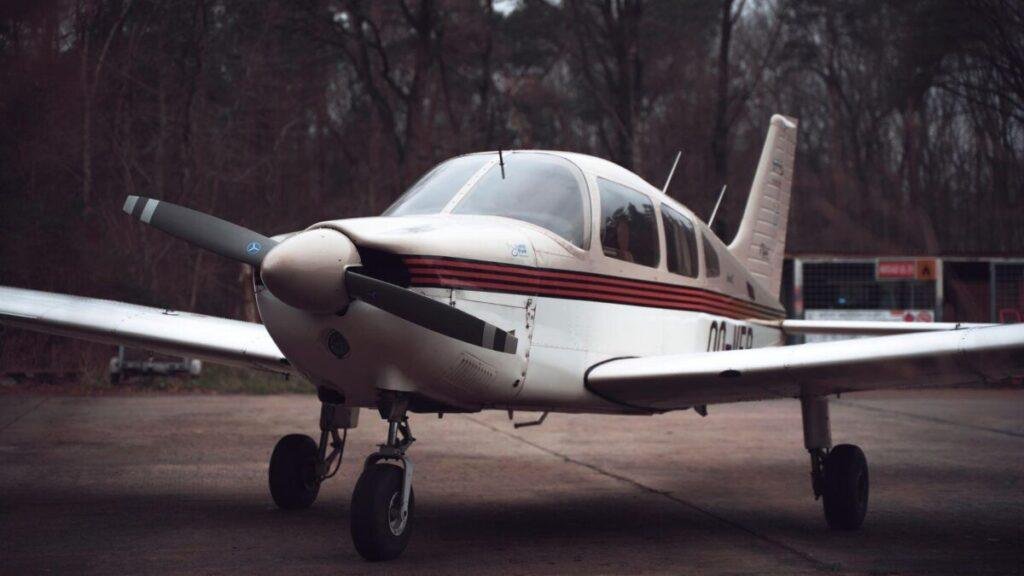 Single-engine propeller airplane parked on a tarmac with trees behind