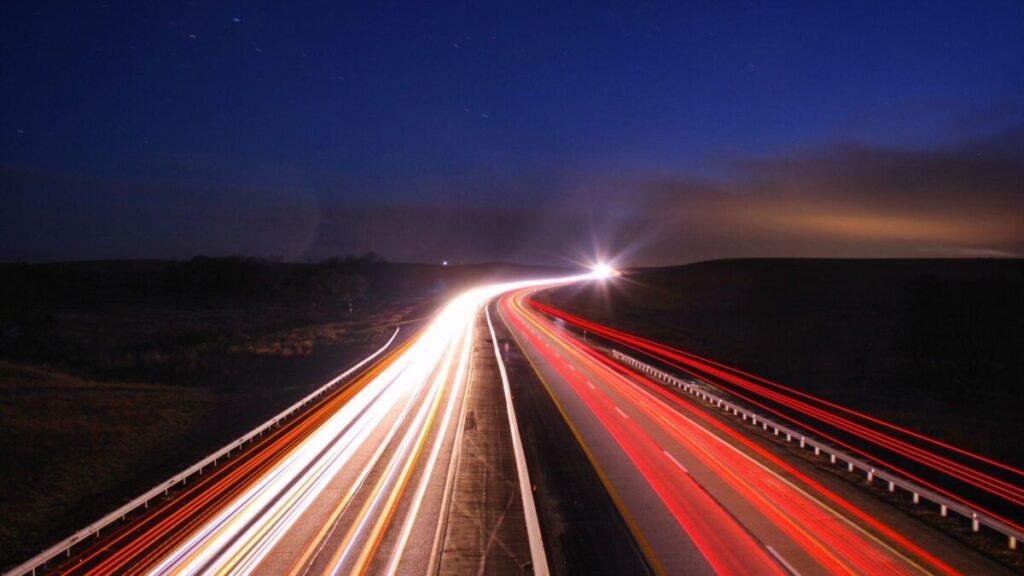 Light trails on a divided highway at night under a clear sky