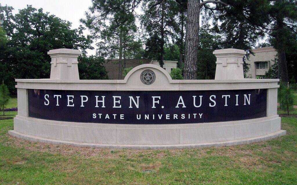 Stephen F. Austin State University stone entrance sign surrounded by tall pines