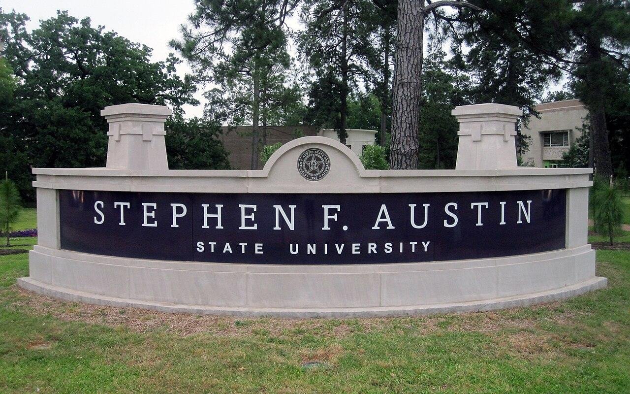 Stephen F. Austin State University stone entrance sign surrounded by tall pines